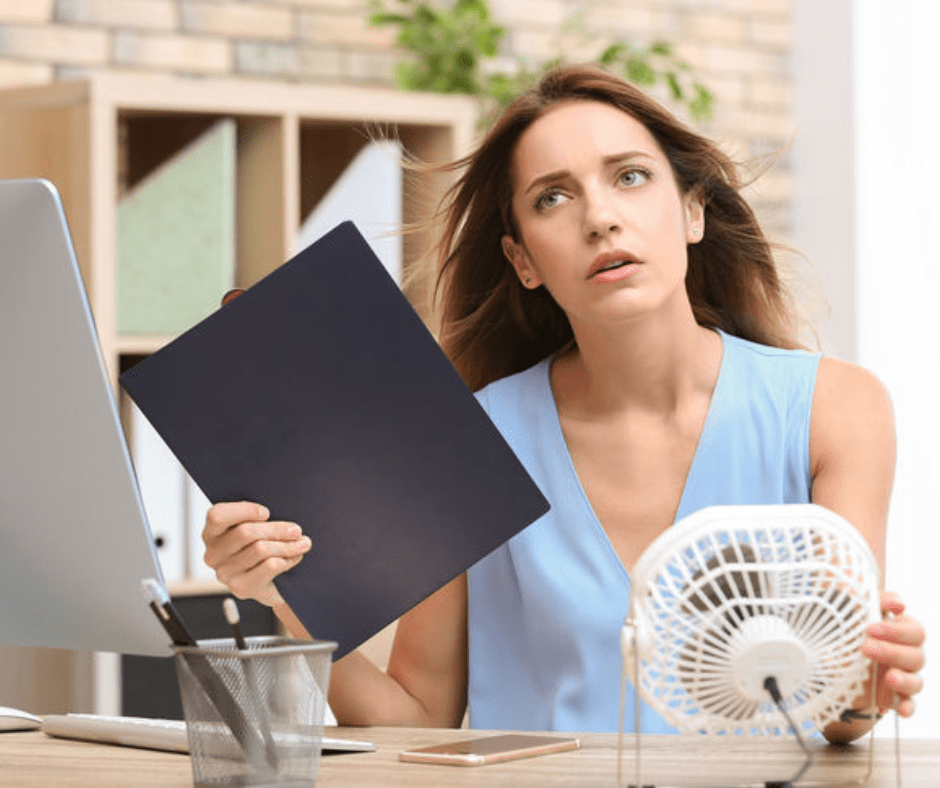 woman fanning herself because AC is blowing hot air